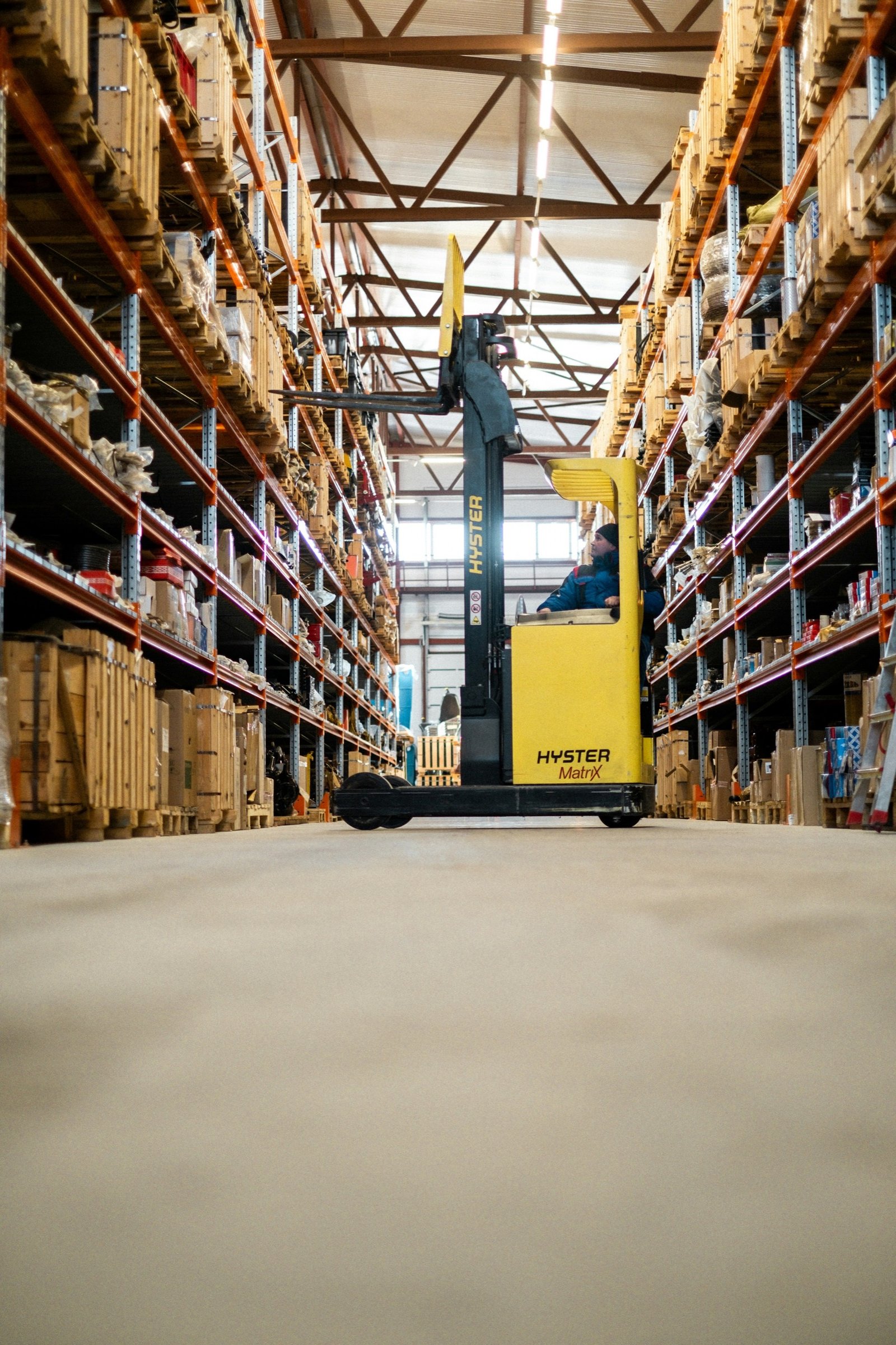 Reach truck moving pallets through a warehouse aisle